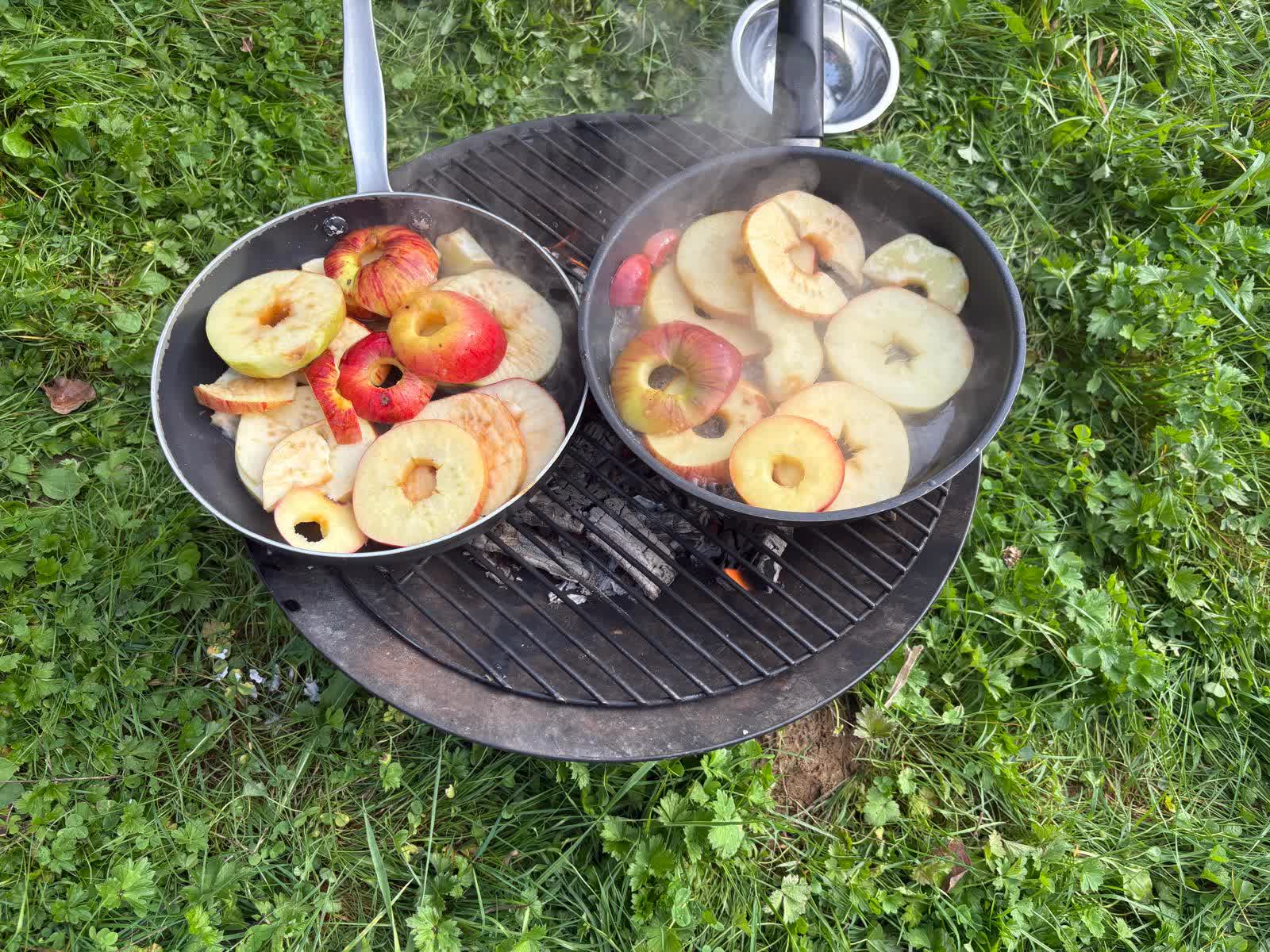 Bratäpfel über dem Lagerfeuer in zwei Pfannen